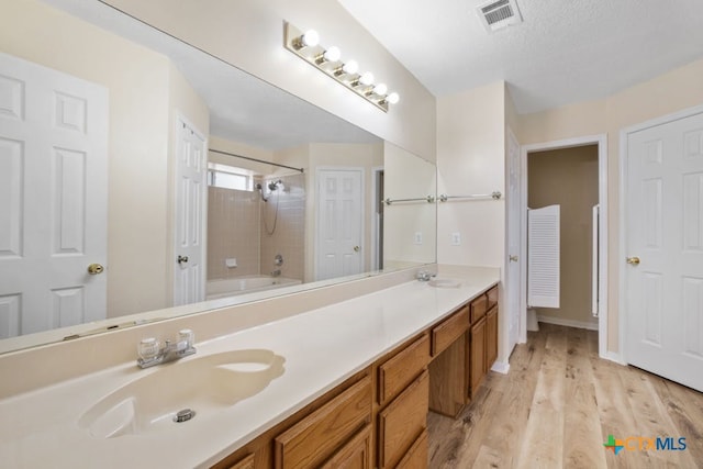 bathroom with vanity, tiled shower / bath combo, and hardwood / wood-style floors