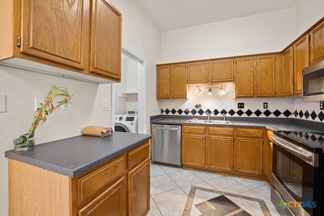 kitchen featuring sink, light tile patterned floors, stainless steel appliances, tasteful backsplash, and washer / dryer