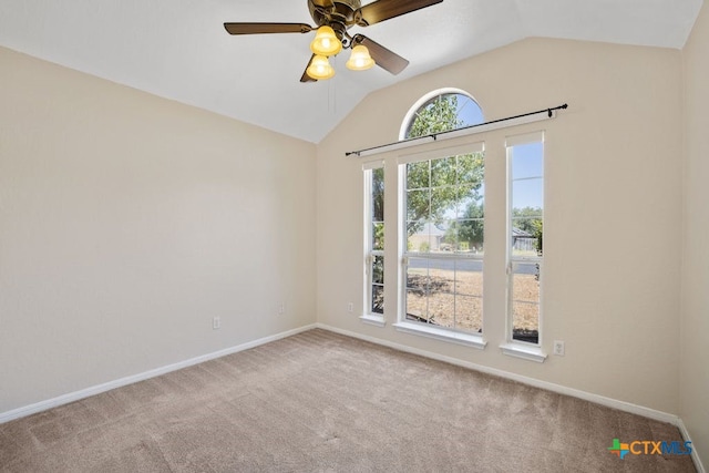 carpeted spare room featuring vaulted ceiling and ceiling fan