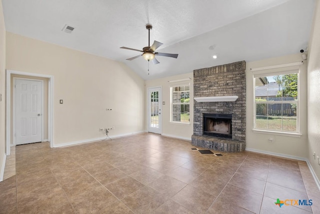 unfurnished living room with vaulted ceiling, a brick fireplace, a healthy amount of sunlight, and ceiling fan