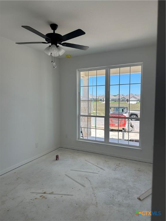unfurnished room with a ceiling fan, baseboards, and concrete floors