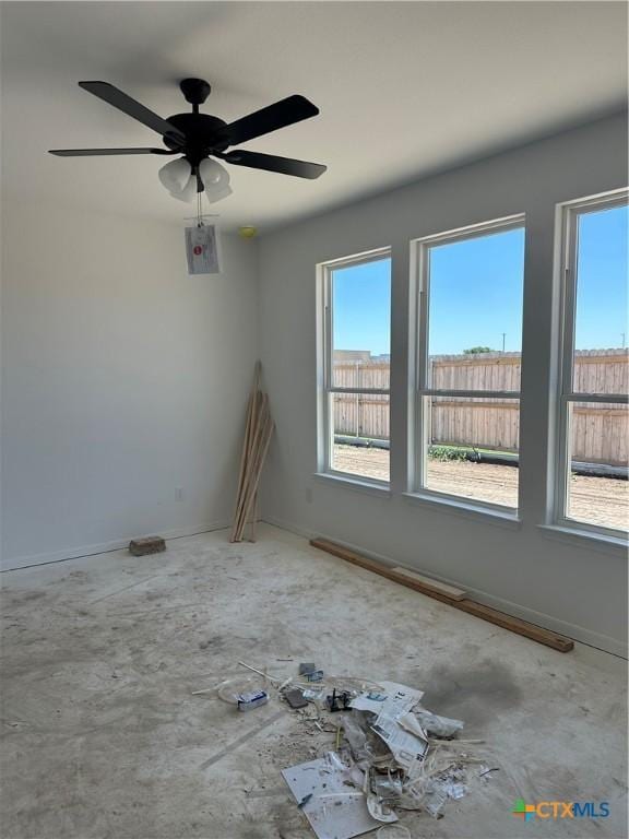 spare room featuring ceiling fan, baseboards, and plenty of natural light
