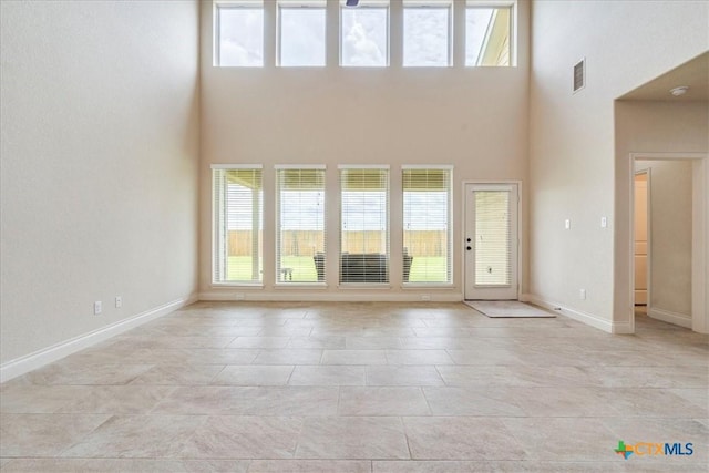 2933 Countryside Path, Seguin, TX 78155 - unfurnished living room featuring healthy amount of natural light, a high ceiling, and light tile patterned flooring