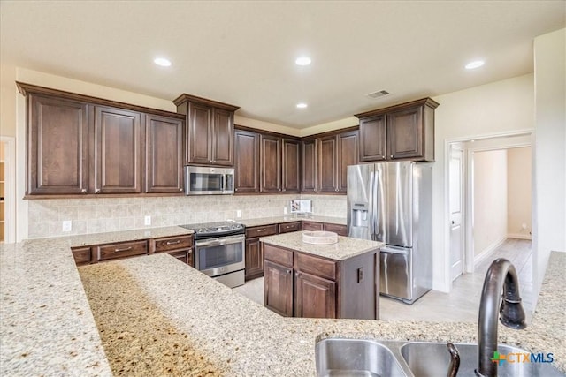 2933 Countryside Path, Seguin, TX 78155 - kitchen with stainless steel appliances, dark brown cabinets, decorative backsplash, recessed lighting, and light stone counters