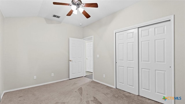 unfurnished bedroom with carpet, baseboards, lofted ceiling, visible vents, and a closet