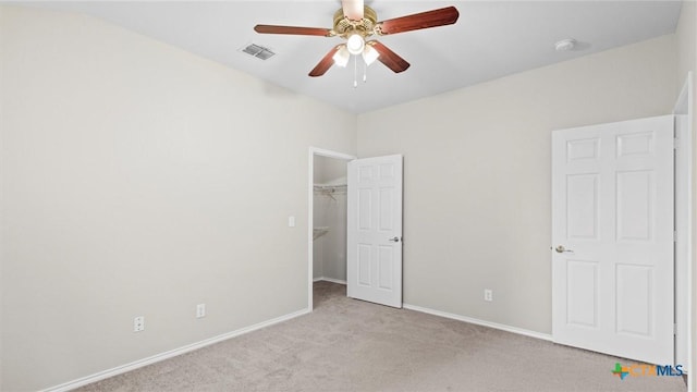 unfurnished bedroom featuring a walk in closet, a ceiling fan, carpet floors, baseboards, and a closet