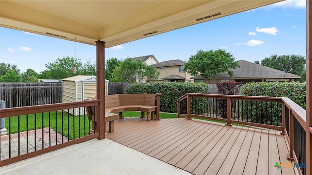 deck featuring a fenced backyard, an outbuilding, visible vents, and a shed