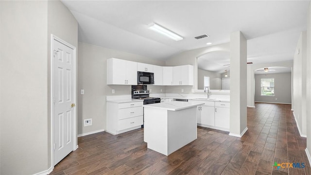 kitchen with electric range, a kitchen island, black microwave, arched walkways, and a sink