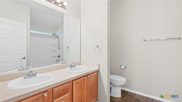 bathroom featuring a sink, baseboards, toilet, and double vanity