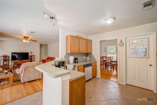 1495 Makinson Rd, La Grange, TX 78963 - kitchen with stainless steel dishwasher, light countertops, a peninsula, light tile patterned floors, and a ceiling fan
