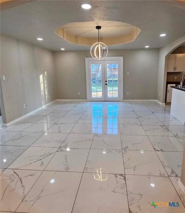 spare room with french doors, a tray ceiling, and a textured ceiling