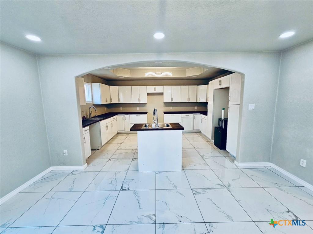 kitchen featuring dishwasher, sink, a kitchen island, and white cabinets