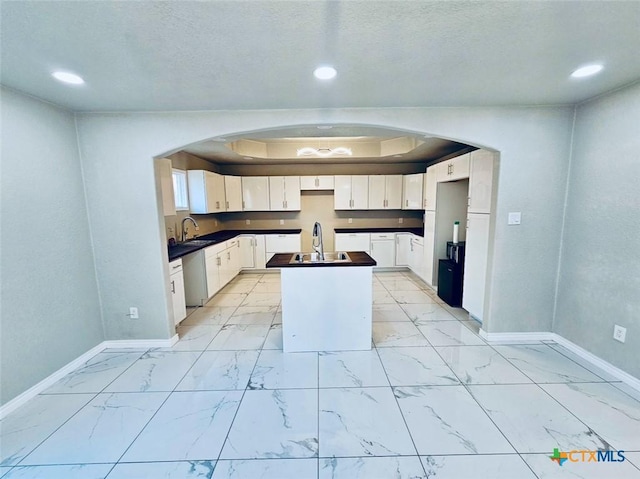 kitchen featuring dishwasher, sink, a kitchen island, and white cabinets