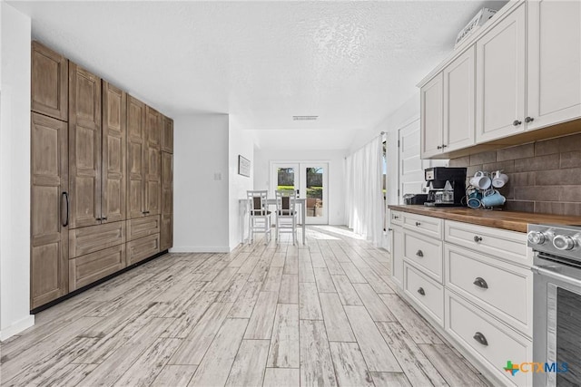 1213 Indian Trl, Salado, TX 76571 - kitchen with french doors, electric range, wood counters, light wood-type flooring, and tasteful backsplash