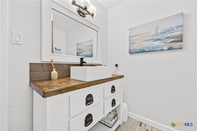 1213 Indian Trl, Salado, TX 76571 - bathroom featuring vanity, wood finished floors, a textured wall, and tasteful backsplash