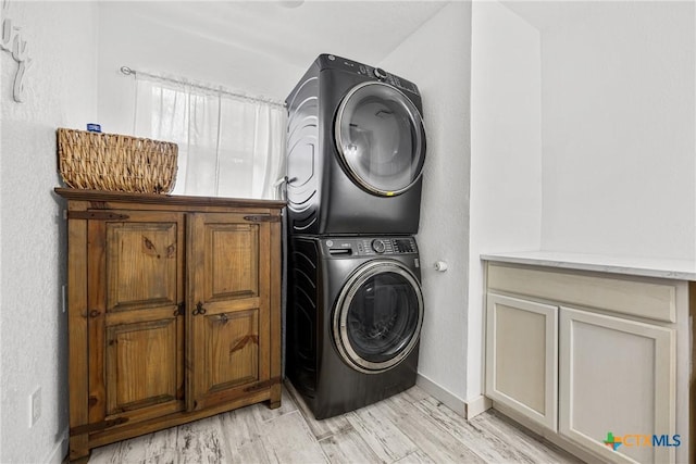 1213 Indian Trl, Salado, TX 76571 - laundry room featuring stacked washing machine and dryer, cabinet space, and light wood-type flooring