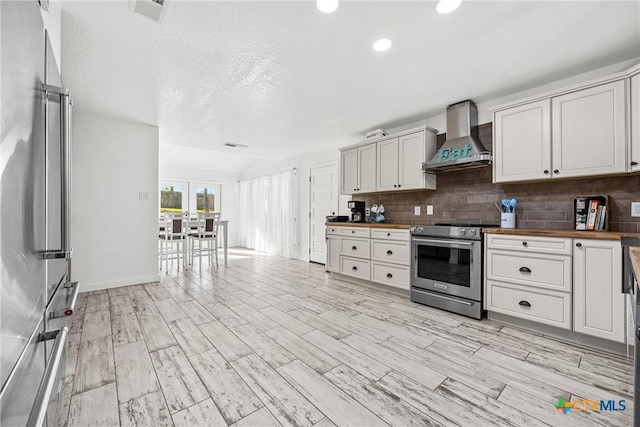 1213 Indian Trl, Salado, TX 76571 - kitchen with appliances with stainless steel finishes, wall chimney range hood, tasteful backsplash, wooden counters, and recessed lighting