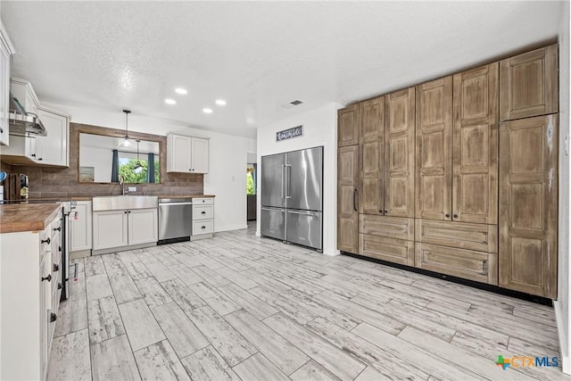 1213 Indian Trl, Salado, TX 76571 - kitchen featuring appliances with stainless steel finishes, backsplash, light wood-style floors, white cabinetry, and recessed lighting