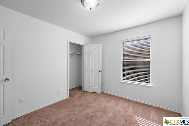 unfurnished bedroom featuring a closet and light colored carpet