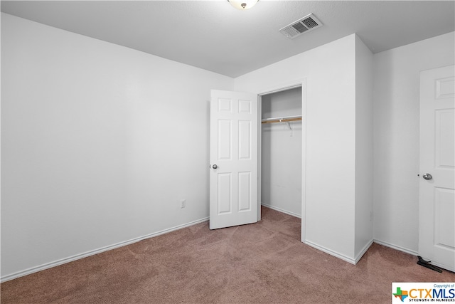 unfurnished bedroom featuring a closet and light colored carpet