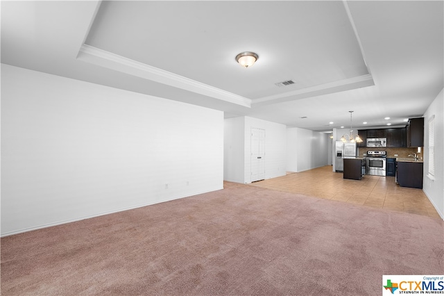 unfurnished living room featuring light colored carpet, a raised ceiling, and a chandelier