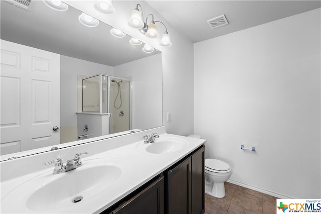 bathroom featuring toilet, vanity, tile patterned floors, and a shower with door