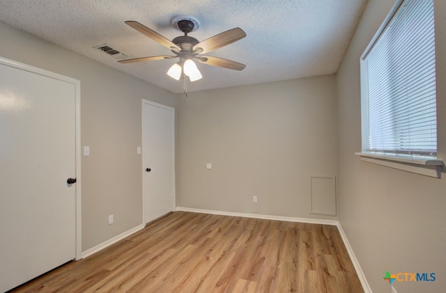 spare room featuring a textured ceiling, light wood-type flooring, and ceiling fan