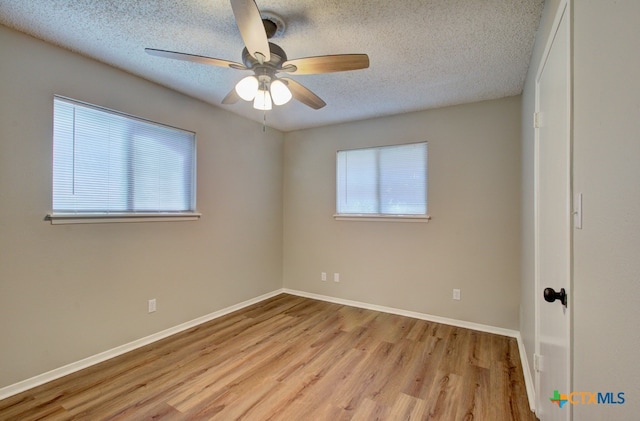 spare room with light wood-type flooring, a healthy amount of sunlight, and ceiling fan