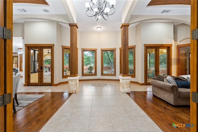 foyer featuring a notable chandelier, light hardwood / wood-style floors, a healthy amount of sunlight, and french doors