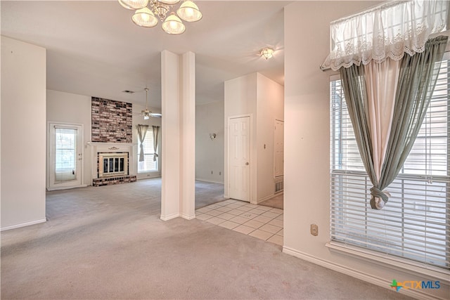 unfurnished living room with a fireplace, light colored carpet, and ceiling fan with notable chandelier