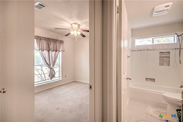 bathroom featuring ceiling fan, tub / shower combination, and toilet