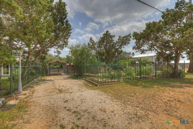 view of yard with a carport, driveway, and fence