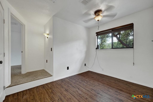 empty room with a ceiling fan, wood finished floors, visible vents, and baseboards