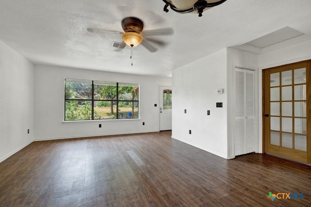 empty room with a ceiling fan, visible vents, baseboards, dark wood-style flooring, and a textured ceiling