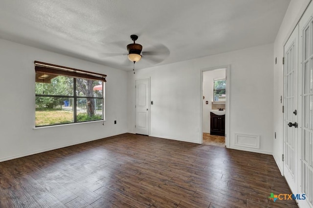 interior space featuring multiple windows, dark wood-style floors, and baseboards