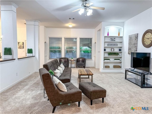 living area featuring a ceiling fan, built in features, carpet, decorative columns, and baseboards