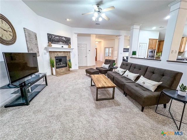 living room with a ceiling fan, visible vents, decorative columns, a tile fireplace, and carpet flooring