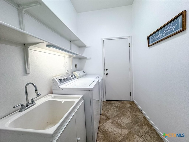 laundry area featuring laundry area, washing machine and dryer, baseboards, and a sink