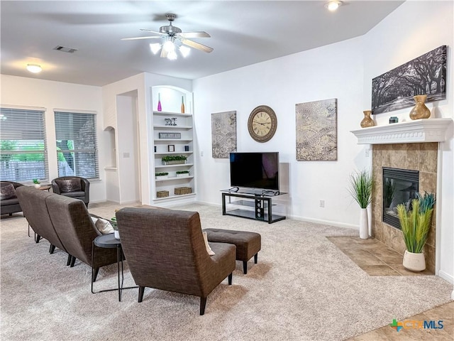 living room with visible vents, built in shelves, baseboards, carpet floors, and a ceiling fan