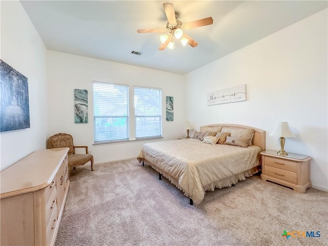 bedroom with visible vents, light colored carpet, baseboards, and ceiling fan