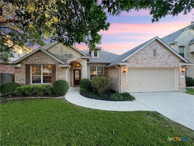 traditional-style home with driveway, an attached garage, a shingled roof, a front lawn, and stone siding