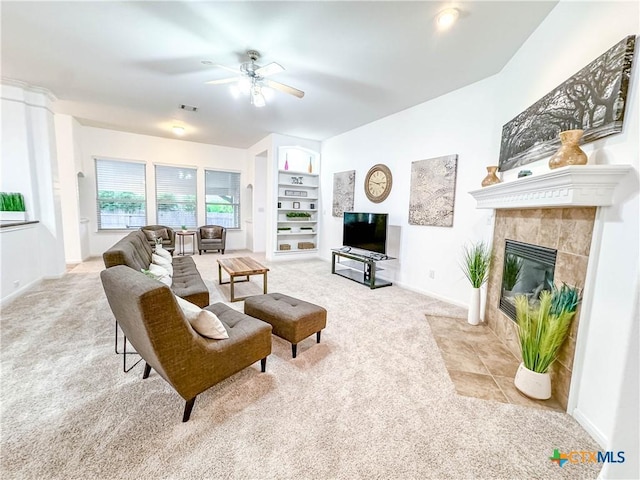 carpeted living area with visible vents, a ceiling fan, built in features, a fireplace, and baseboards