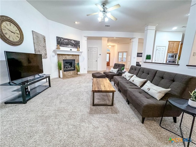 living area featuring visible vents, decorative columns, ceiling fan, a tiled fireplace, and carpet flooring