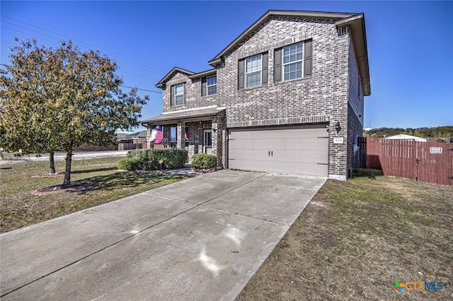 traditional home with a front lawn, driveway, fence, a garage, and brick siding