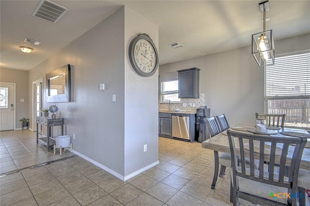 kitchen with tasteful backsplash, light tile patterned floors, gray cabinets, and dishwasher