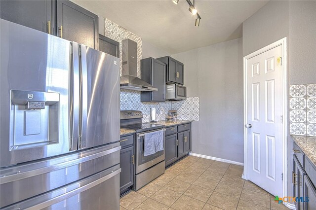 kitchen featuring stainless steel appliances, light stone counters, light tile patterned flooring, decorative backsplash, and wall chimney exhaust hood