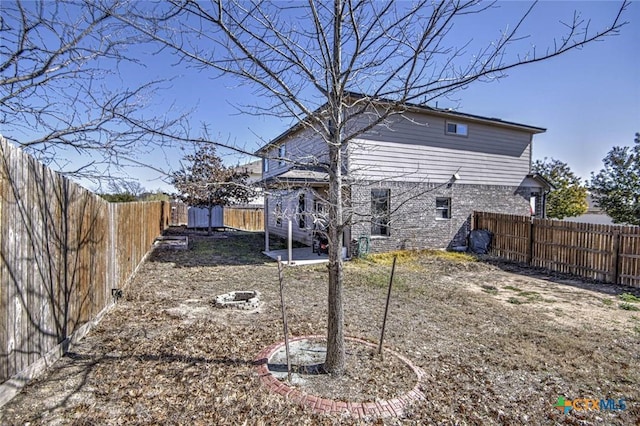 rear view of property with a fenced backyard and a fire pit