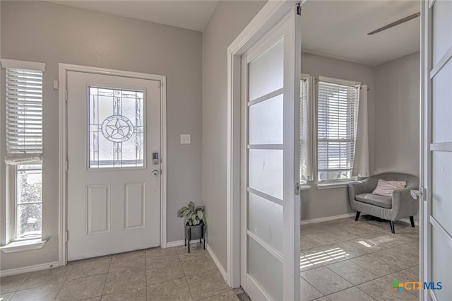 entryway featuring light tile patterned floors, baseboards, and a ceiling fan