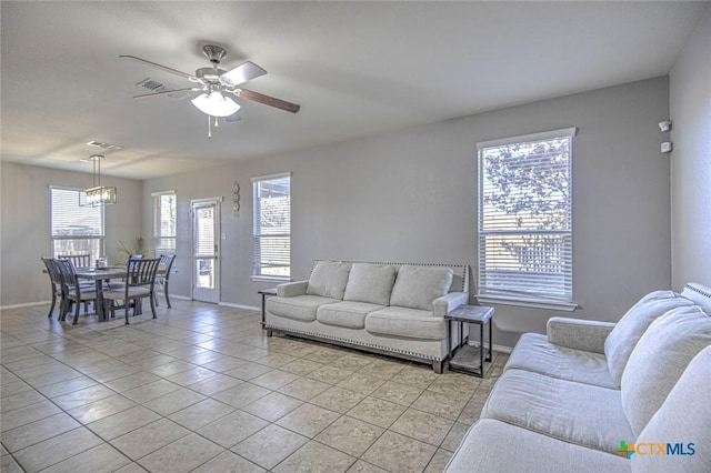 tiled living room with ceiling fan with notable chandelier