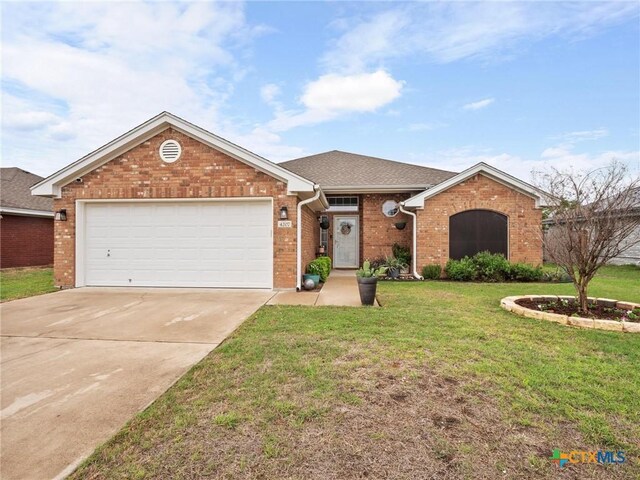 ranch-style house featuring a front lawn, an attached garage, brick siding, and concrete driveway